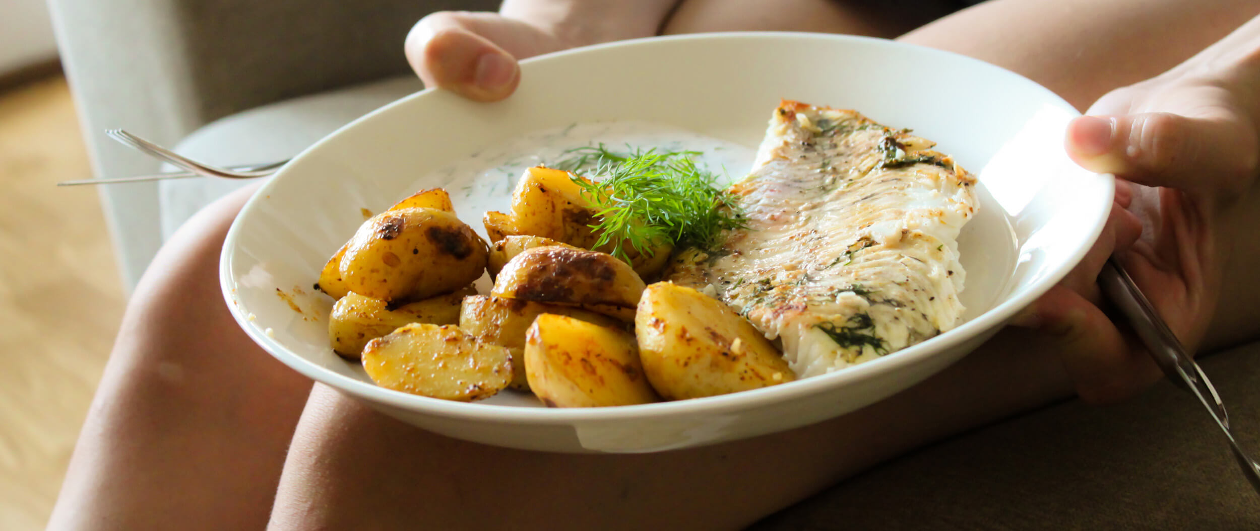 Henkilö pitelemässä annosta kalakeittoa lautasella.